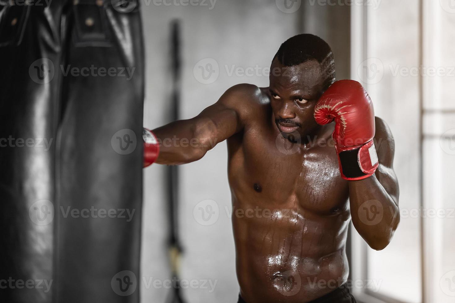 afrikansk man tränar på gym och knytnävar hans boxningsväska knytnävar. sport man träning på gym, fitness, boxning, framgång, träning och kraft foto