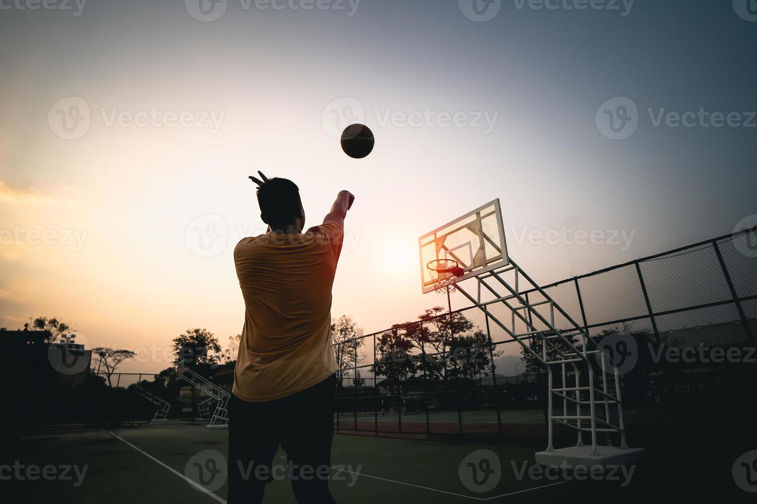 basketspelare siluett vid solnedgången. basketspelare skjuter ett skott. sport basket koncept. foto