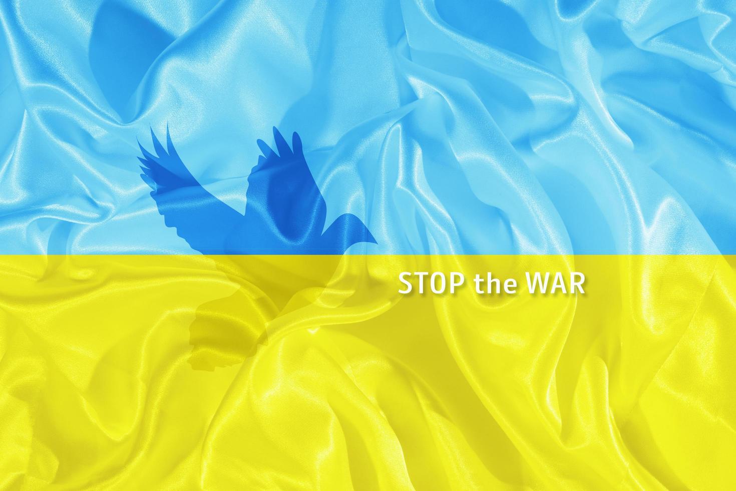 stoppa krigstexten på den blå och gula ukrainska flaggan med siluetten av fredsduvan foto