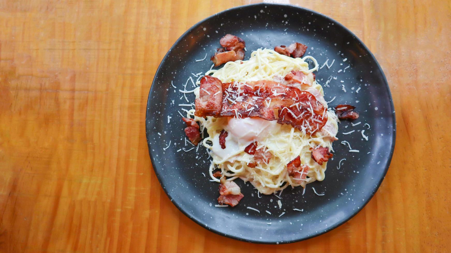 carbonara spagetti med onsenägg, knaperstekt bacon, hård parmesanost och gräddsås. foto