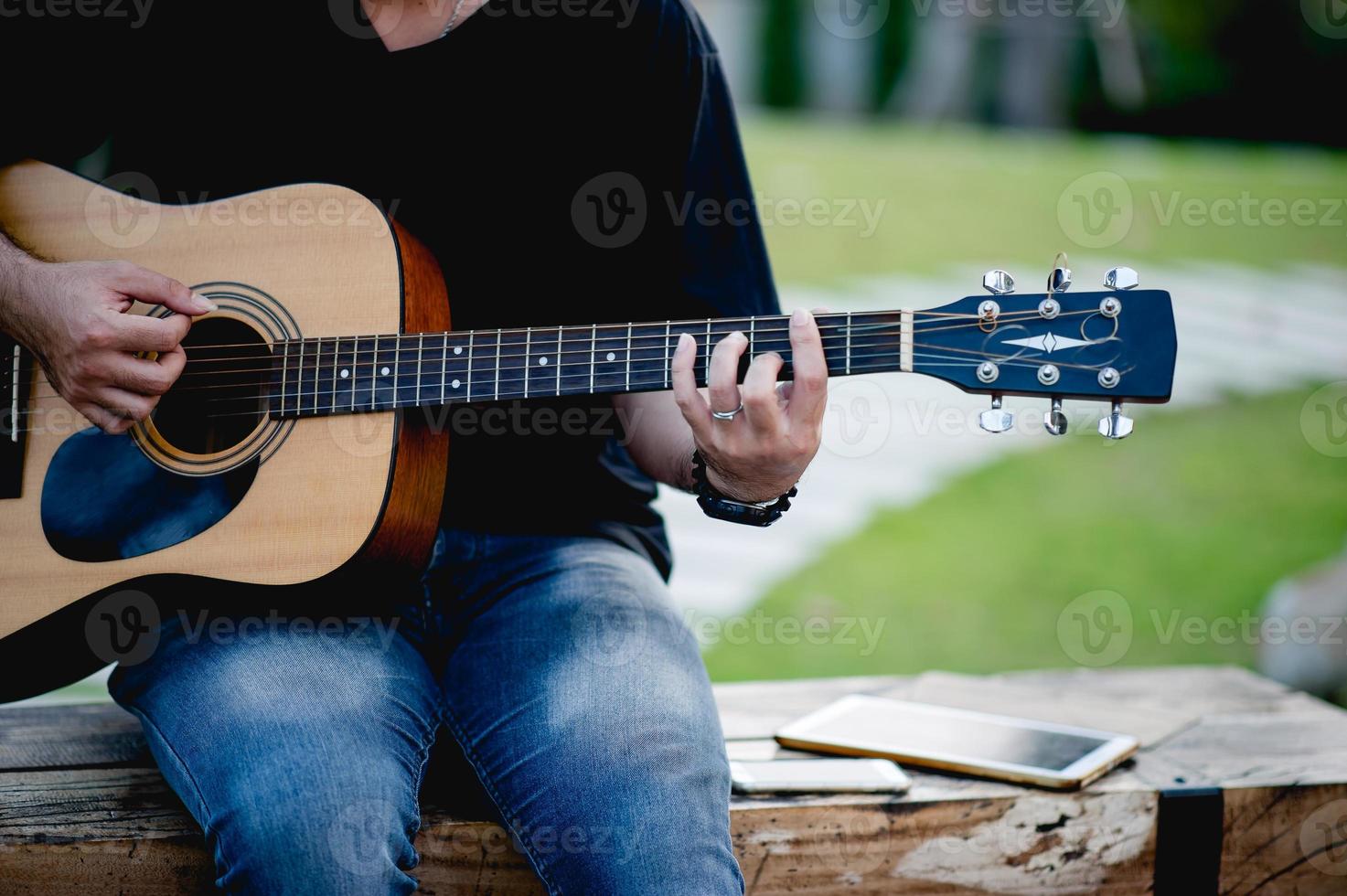 bild av en gitarrist, en ung man som spelar gitarr medan han sitter i en naturlig trädgård, musikkoncept foto