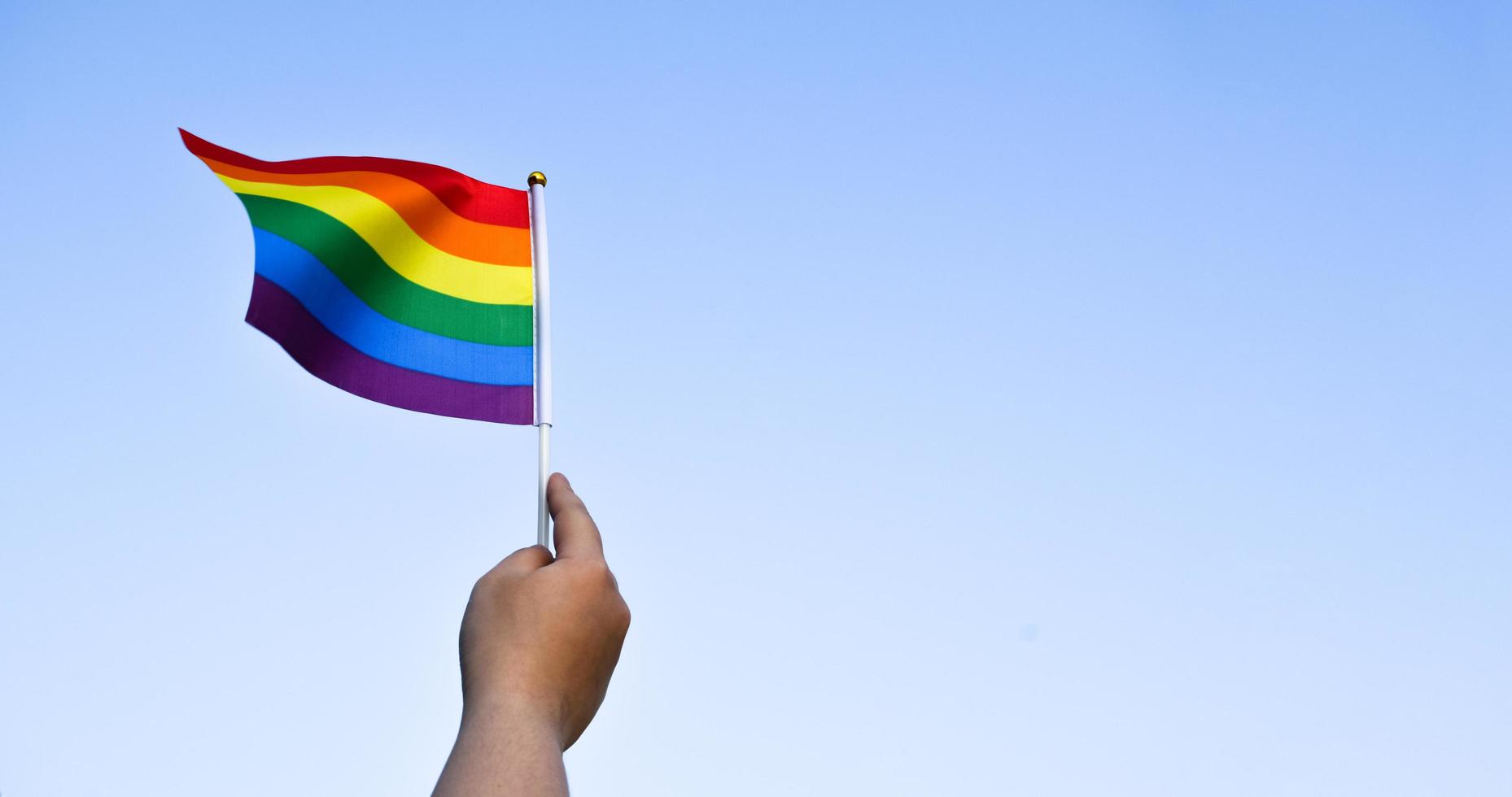 regnbågsflagga, en symbol för hbt-gemenskapen, vinkar i vinden med oskärpa asiatiska studenter i bakgrunden för morgonaktiviteter. koncept för att stödja och driva kampanj för hbt-samhällen i skolan foto