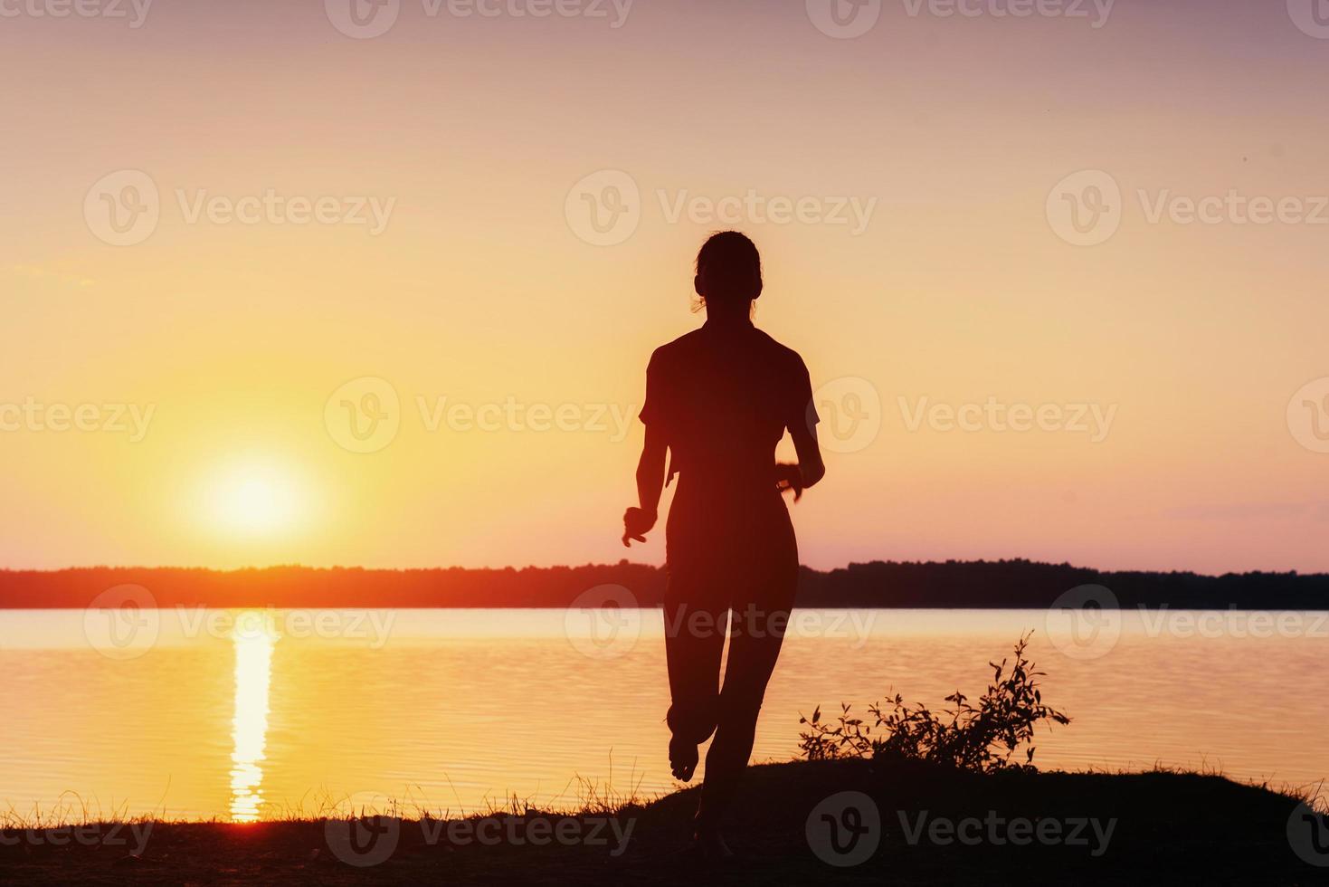 flicka vid solnedgången vid sjön. foto