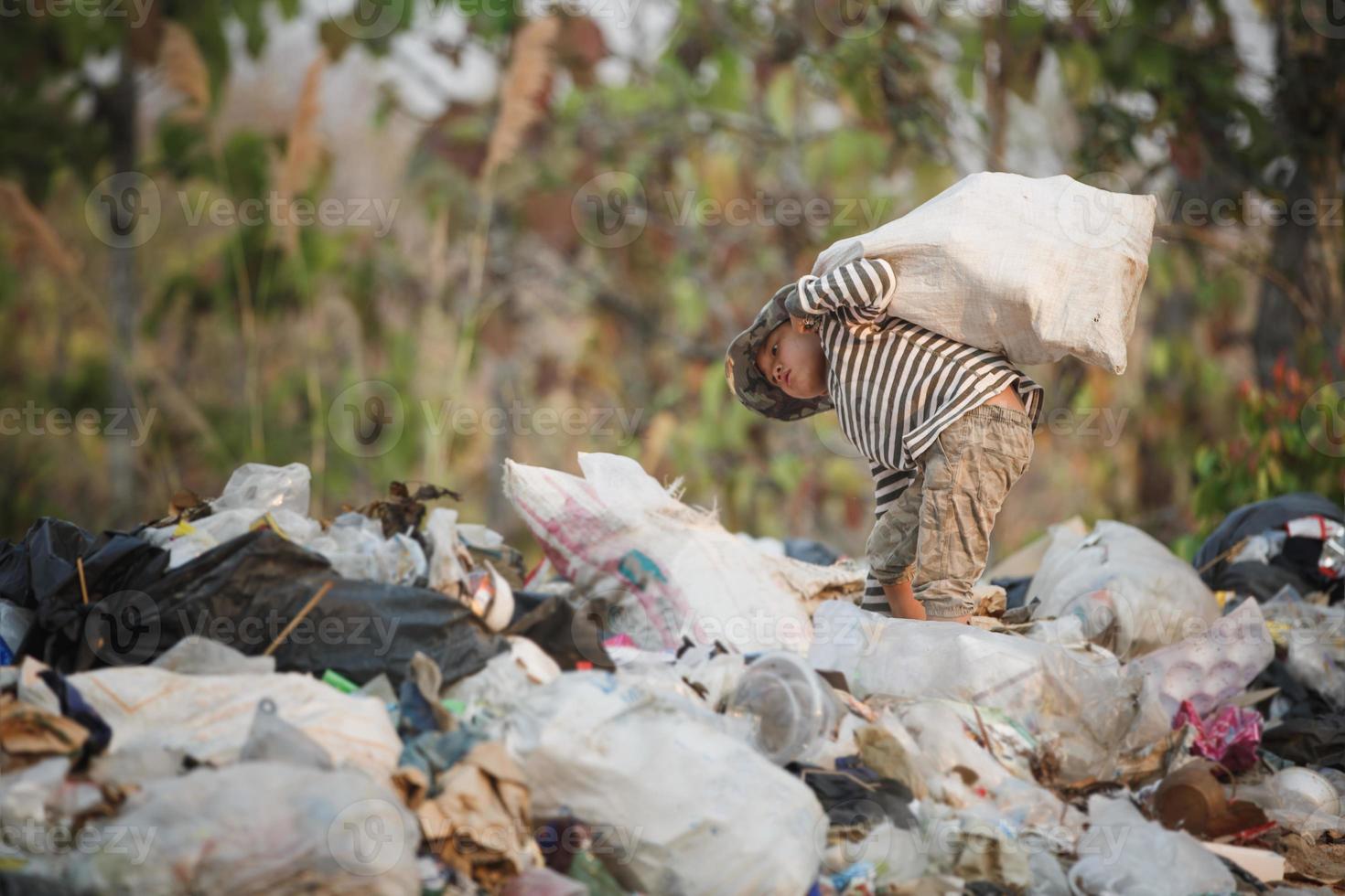 en fattig pojke samlar skräp för att sälja. liv och livsstil för det fattiga konceptet barnarbete, fattigdom, miljö. avfallssortering. foto