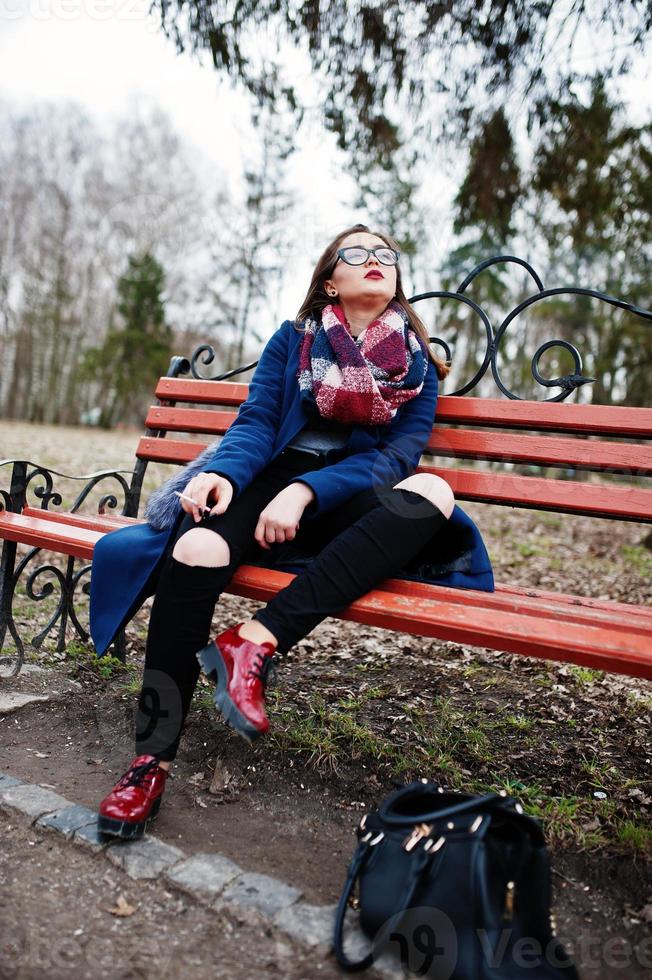 ung flicka röka cigarett utomhus sitter på bänken. koncept av nikotinberoende av tonåringar. foto