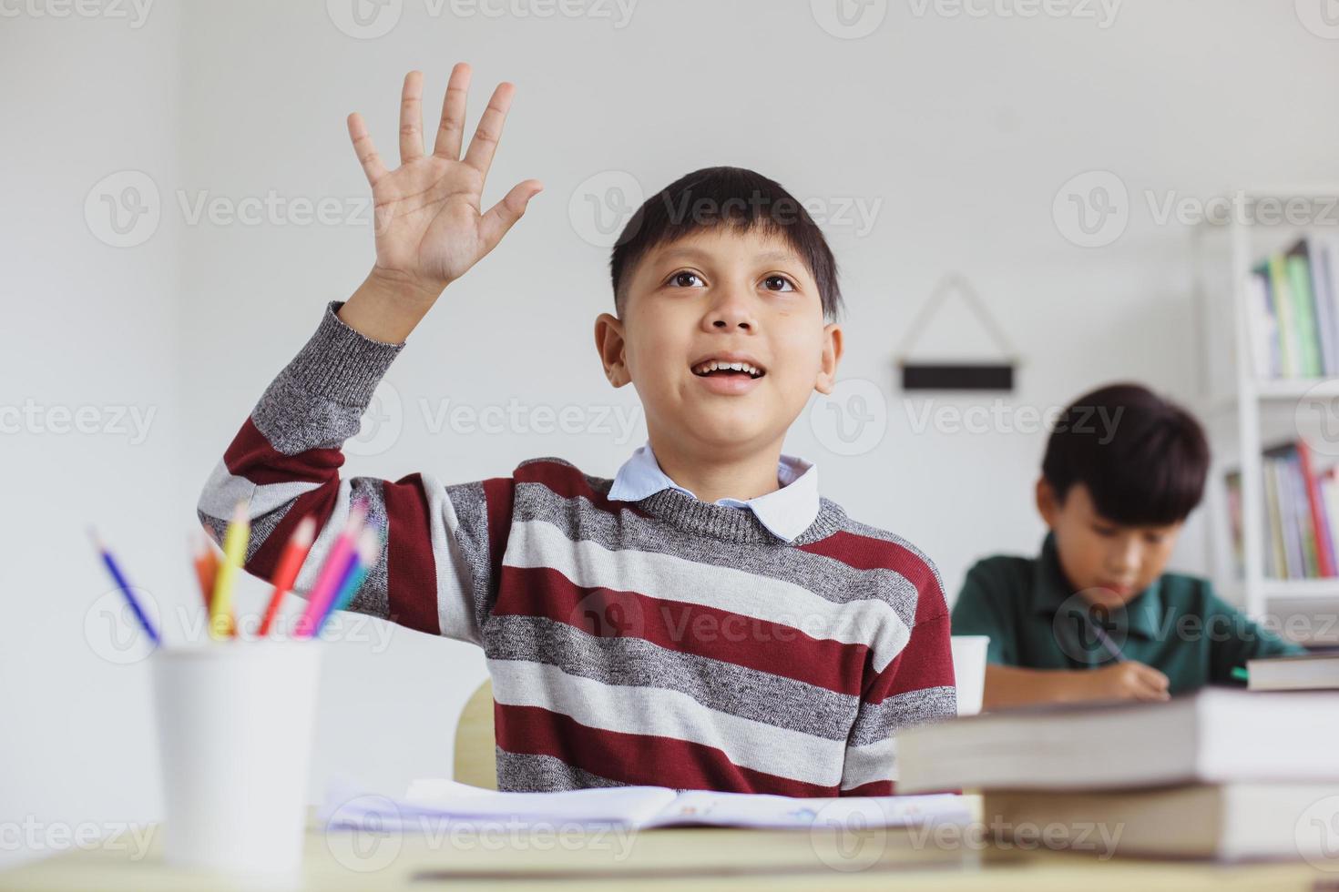 smart och aktiv asiatisk student räcker upp handen under lektionen för att svara på frågan foto