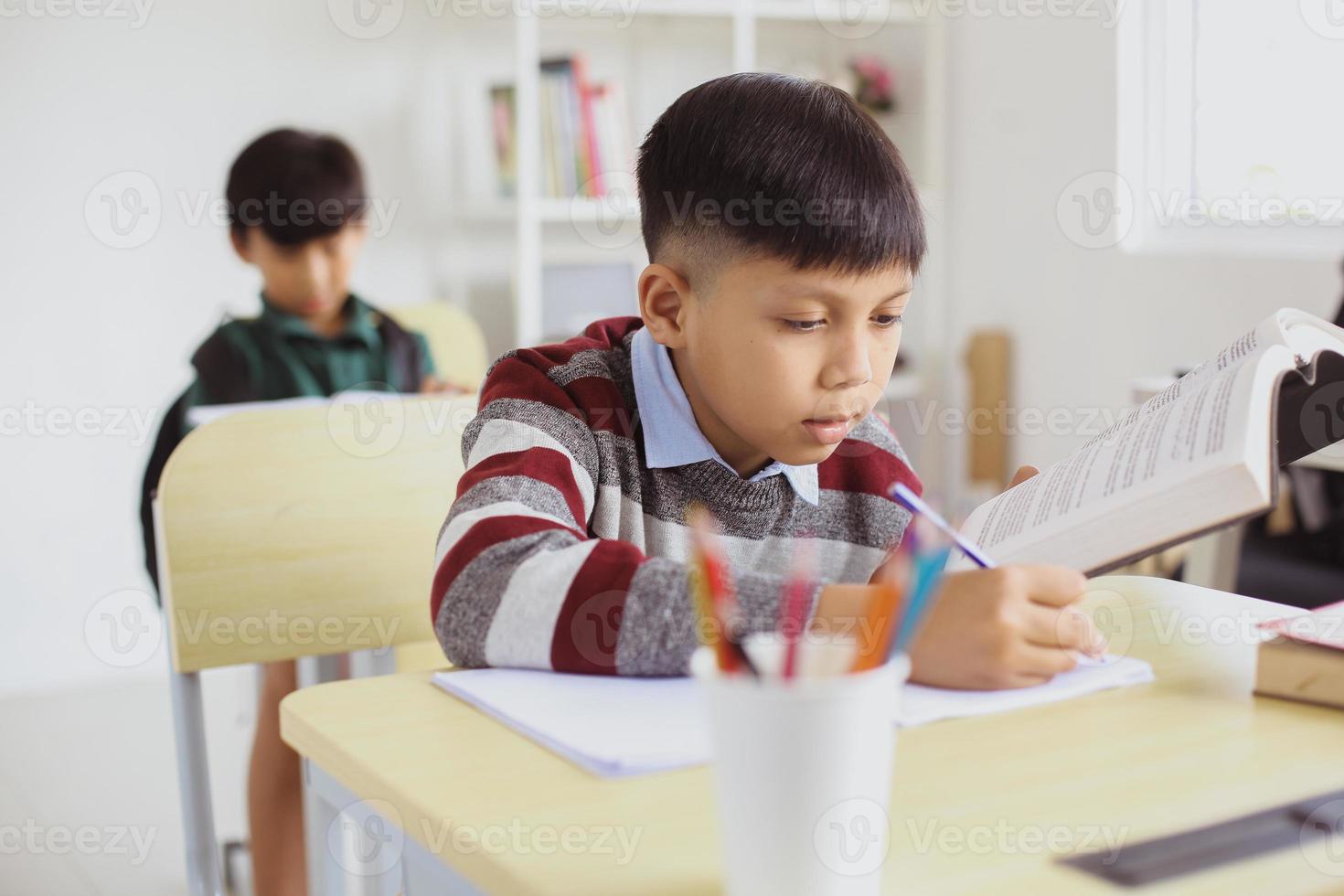 seriös asiatisk student gör uppgift i klassrummet foto