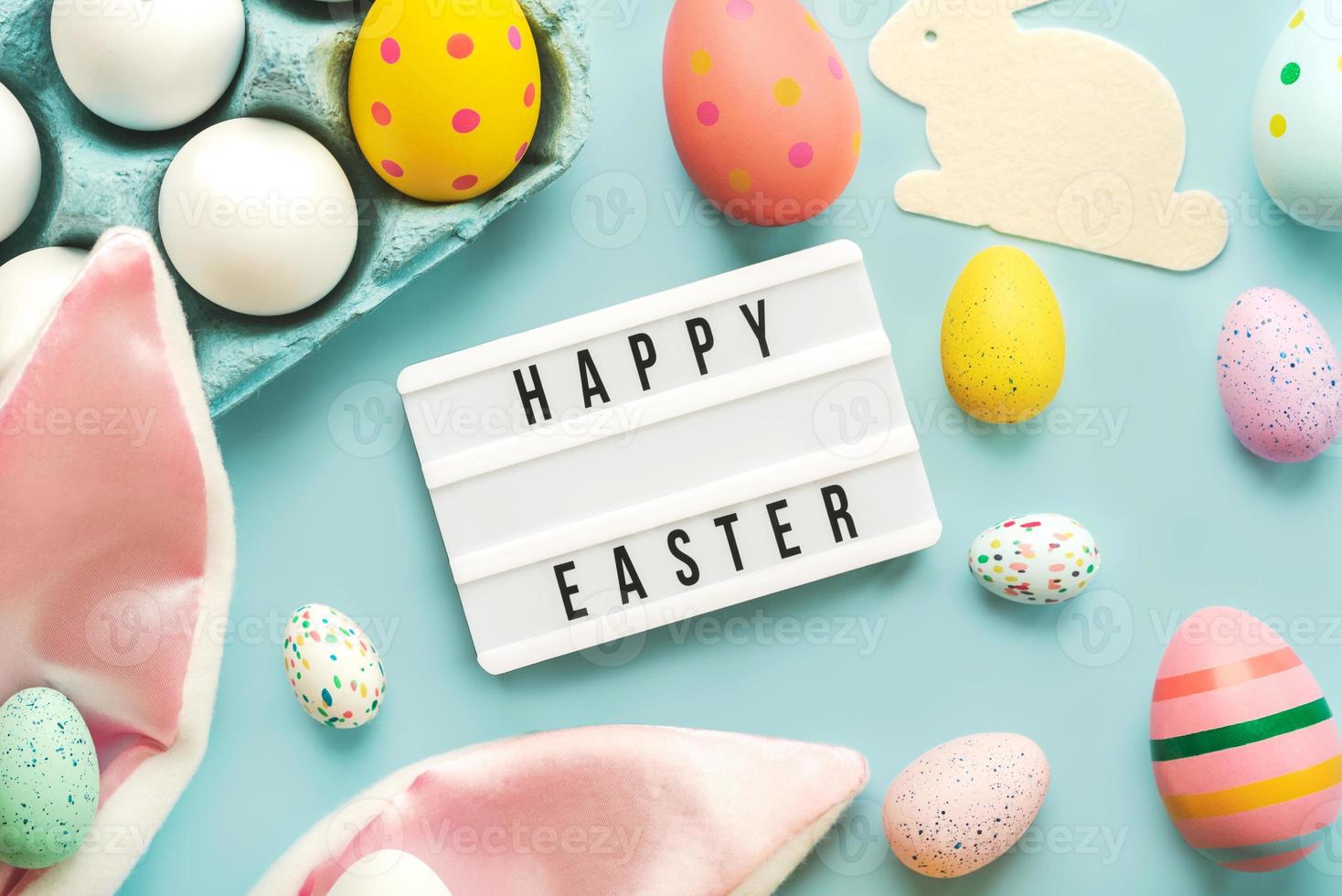 glad påsk. ljuslåda med texten glad påsk, färgade påskmålade ägg och kaninöron foto