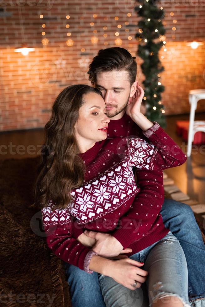 man och fru i identiska stickade tröjor har roligt tillsammans och firar jul. foto