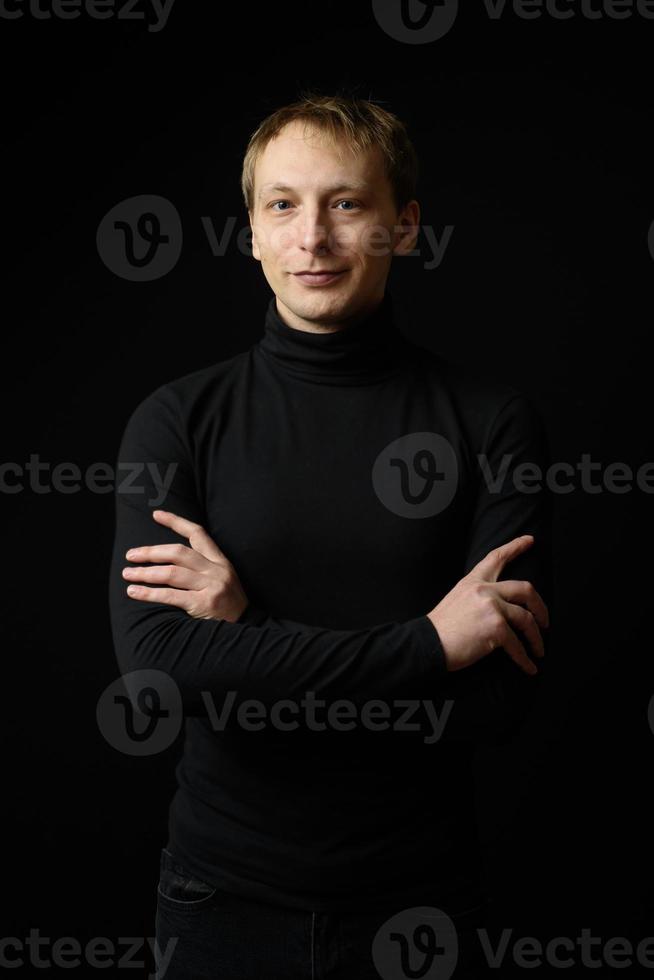 porträtt av bestämd snygg man klädd i svart skjorta, svart bakgrund. foto