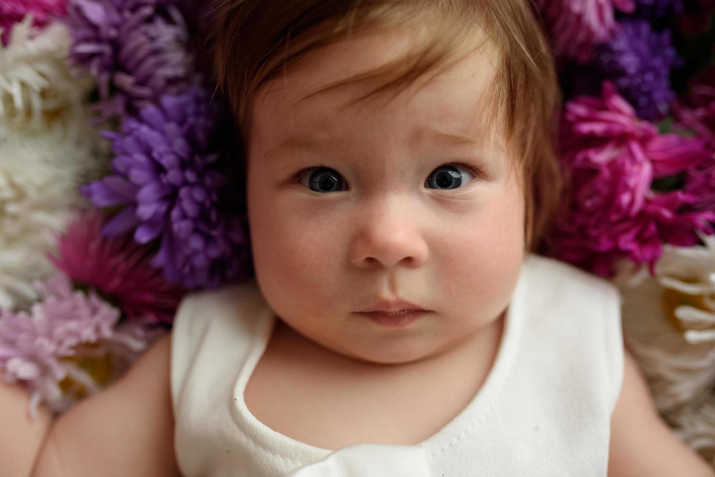 flicka i blå klänning leker med en massa rosa tulpaner. litet barn hemma i solig barnkammare. toddler ha kul med blommor foto