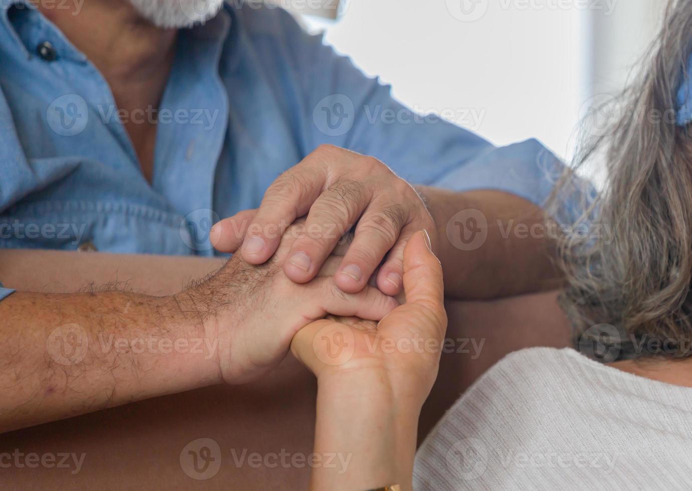 äldre asiatiska par som håller handen medan du sitter tillsammans i vardagsrummet hemma, lycka familj koncept foto