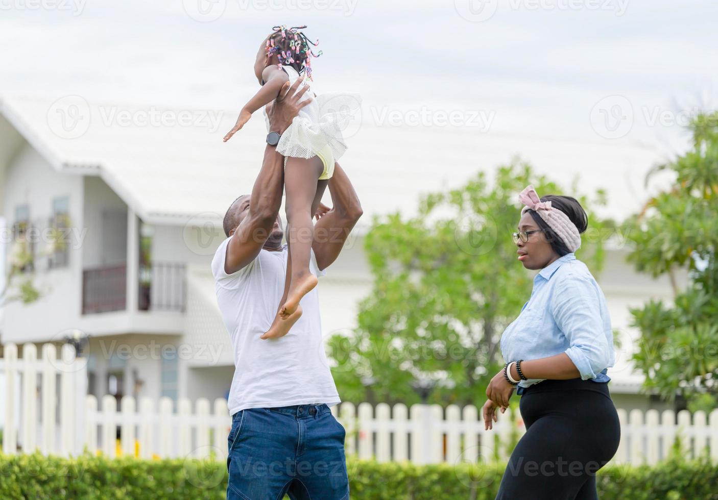 glad far mor och dotter leker tillsammans utomhus, glad afrikansk amerikansk familj som njuter i parken, lycka familjekoncept foto