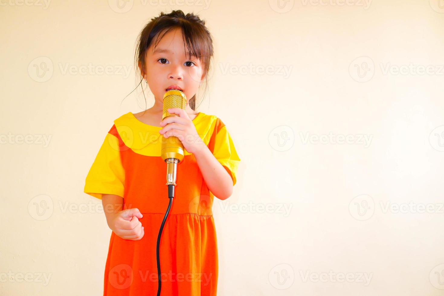 härlig baby flicka bär gul-orange outfit gokowa outfit eller mugunghwa, och hålla guld mikrofon sjunga musik. flickor och tonåring mode klänning. foto