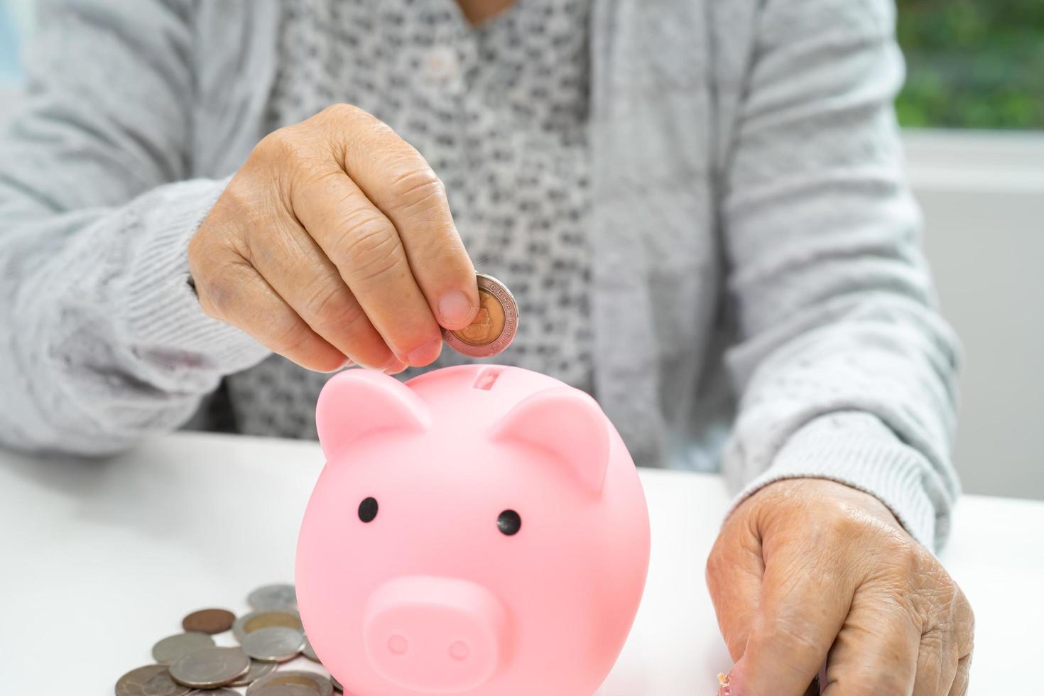 asiatisk senior eller äldre gammal dam kvinna håller räknar mynt pengar i spargris. fattigdom, sparproblem vid pensionering.. fattigdom, sparproblem vid pensionering. foto