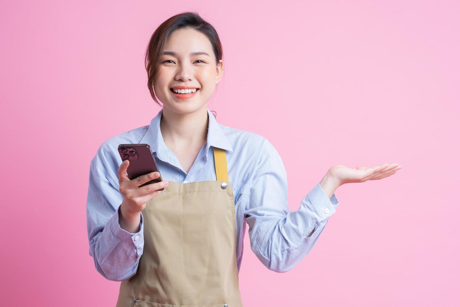 ung asiatisk servitris stående på rosa bakgrund foto