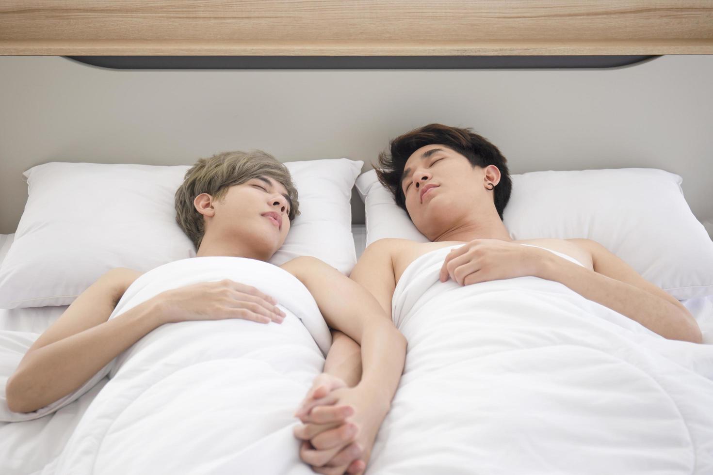 ett manligt par med en asiatisk man som gosar bredvid sin säng, en symbol för sexuell mångfald, som uttrycker öppet homosexuella män som accepterar hbt-koncept. foto