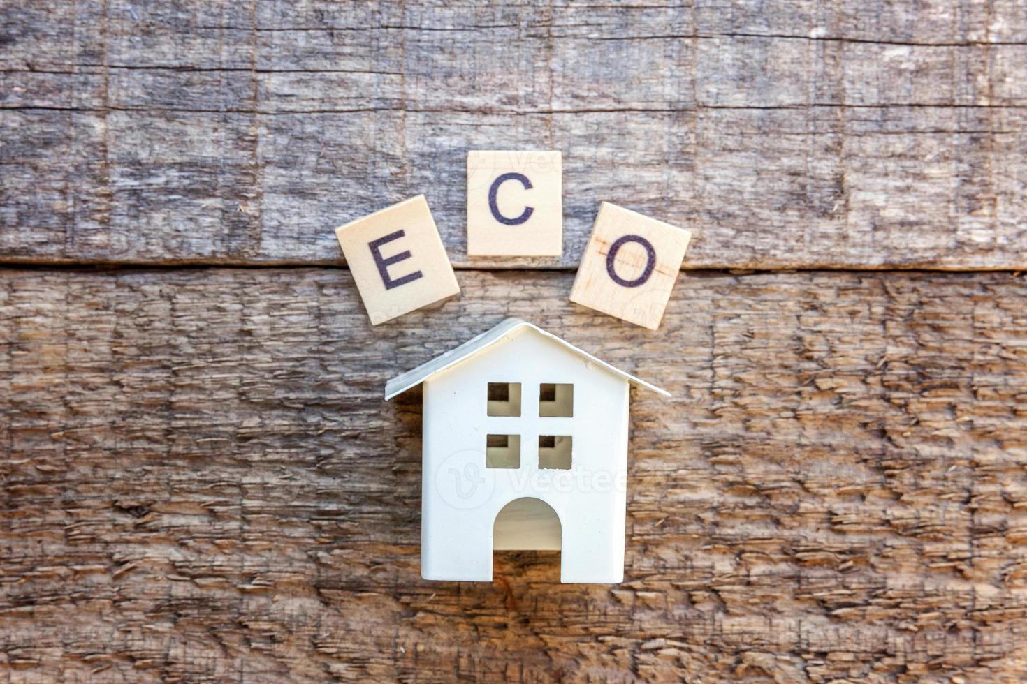 miniatyr leksak modell hus med inskription eco bokstäver ord på trä bakgrund foto
