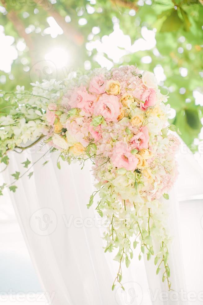 färgglada rosa och ljusgröna blomsterarrangemang knutna till en båge i en bröllopsceremoni foto