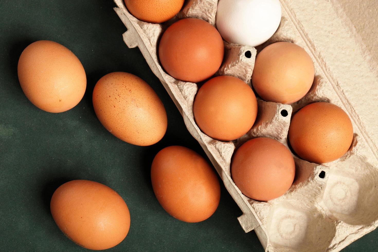 närbild av råa kycklingägg brunt och vitt i låda, äggbrunt på grön bakgrund foto