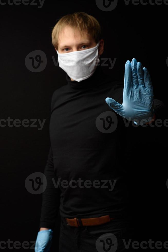 medelålders man i medicinsk mask visar ett stopp med handen. begreppet skydd mot coranavirus. foto