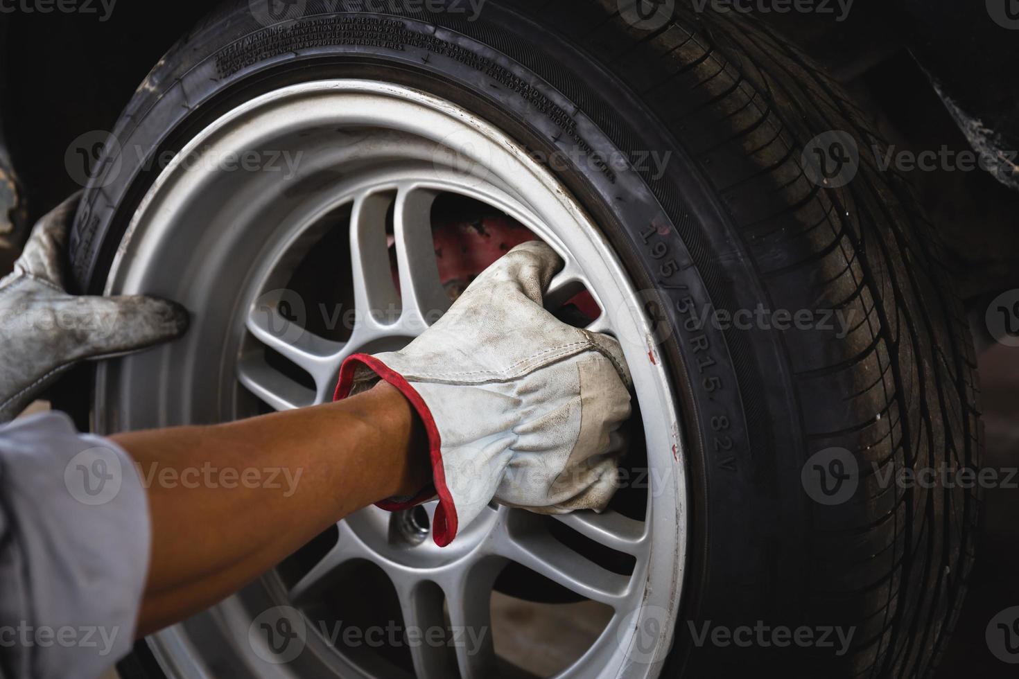 närbild av reparationsmekanikerns händer under underhåll och byte av däck på en bil foto