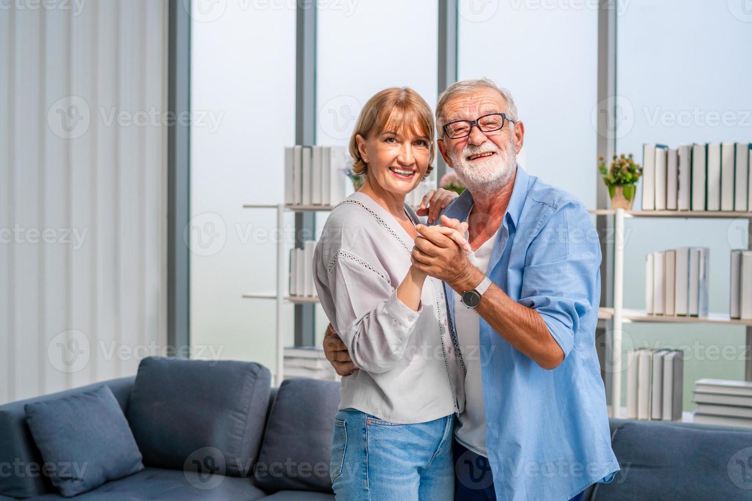 porträtt av lyckliga äldre par som dansar i vardagsrummet, äldre kvinna och en man som dansar, lyckliga familjekoncept foto