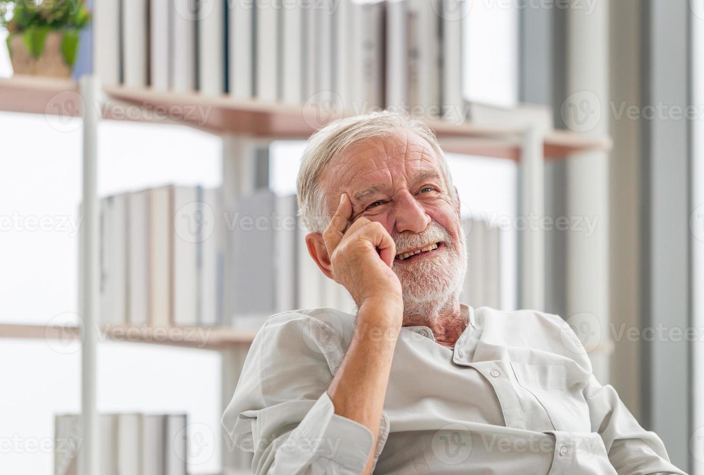 porträtt av leende senior man kopplar av och njuter i vardagsrummet foto