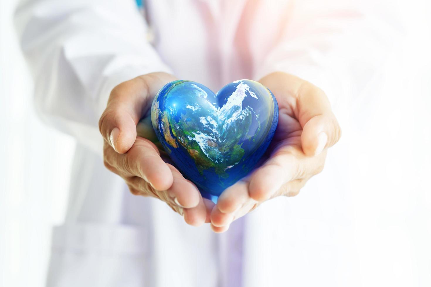 händerna håller jordklotet i hjärtform på läkarens händer för innehållet i världshälsodagen och kopiera space.elements av denna bild från nasa foto