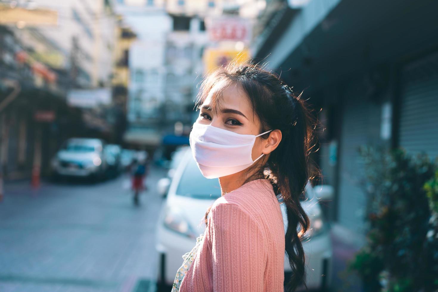 glad asiatisk vuxen kvinna solbränna hud bär mask i ansiktet för nya normala. foto