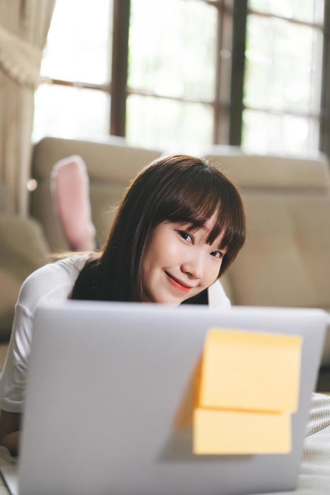 glad asiatisk tonåringskvinna arbetar och studerar online via internet hemma. foto