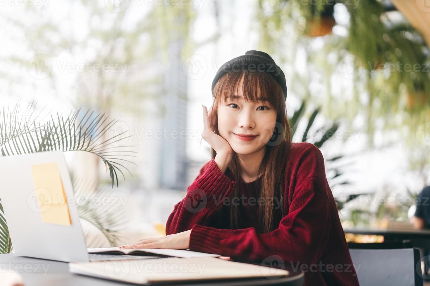 porträtt av ung vuxen asiatisk college student kvinna med laptop för studier på café på vinterdagen. foto