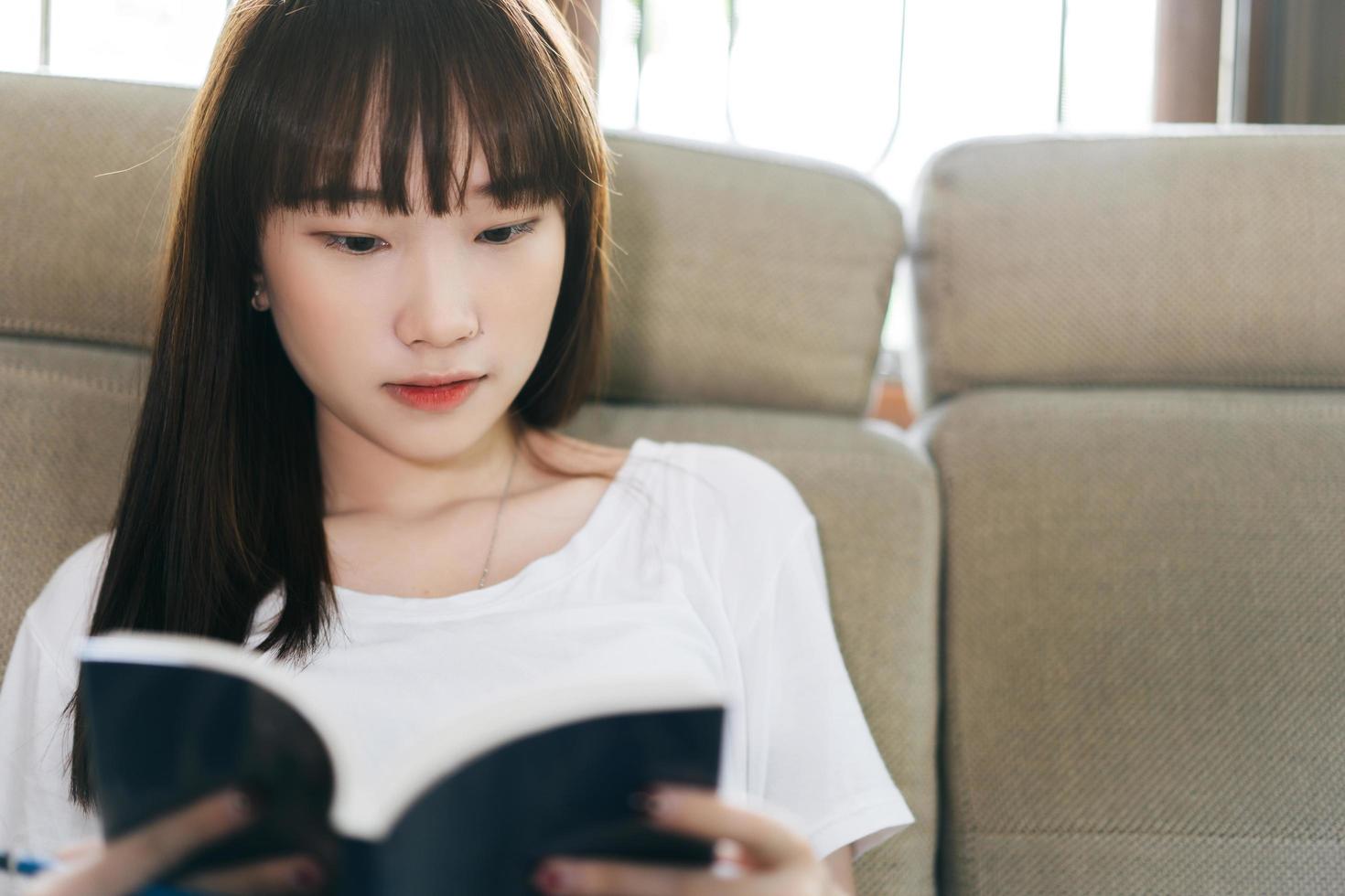 asiatisk tonåring student kvinna läser bok studie form hem. foto