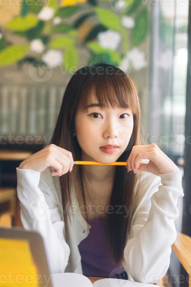 porträtt av asiatisk tonåring högskolestudent kvinna som studerar på café. foto