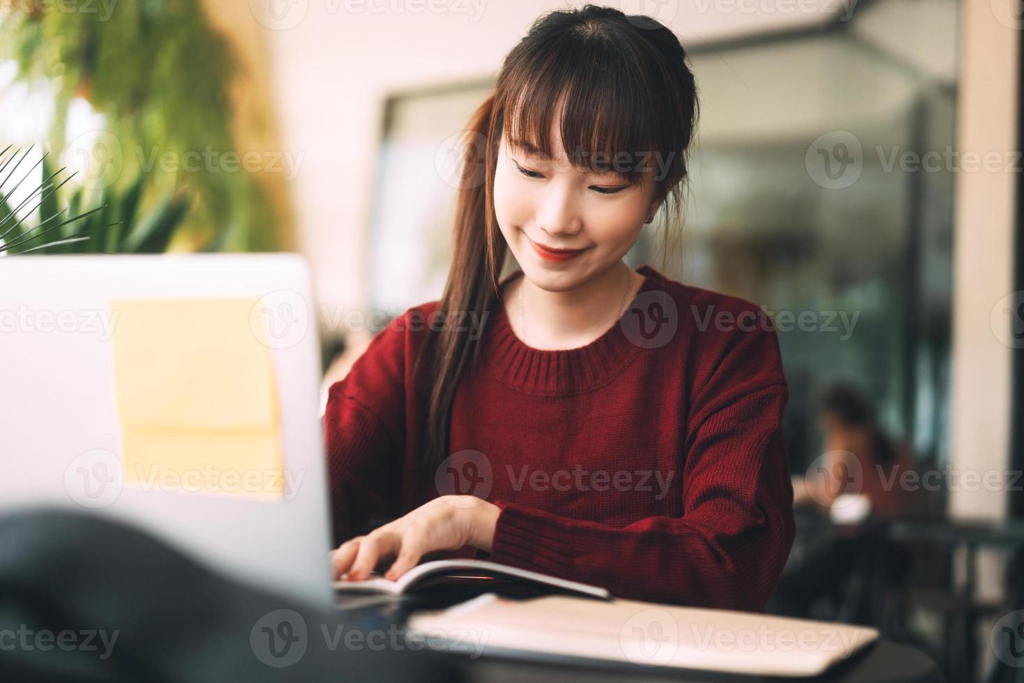 ung vuxen asiatisk college student kvinna med laptop för studier på café på vinterdag. foto