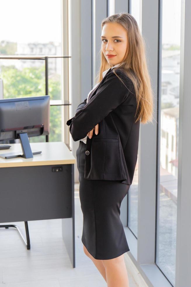 en vacker ung affärskvinna som står bredvid en glasvägg på ett kontor foto