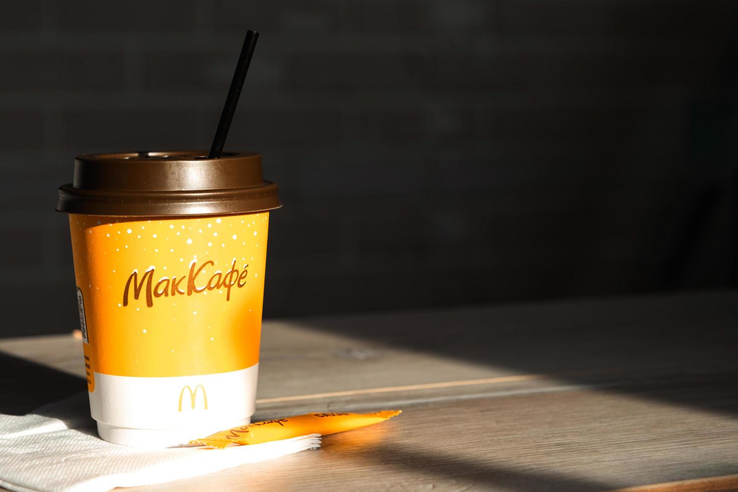 kaffe att gå på mcdonald's med inskriptionen maccafe i rysk pinne med socker på bordet med en servett och ett sugrör. snabbmatsrestaurangskedjor. Ryssland, Kaluga, 21 mars 2022. foto