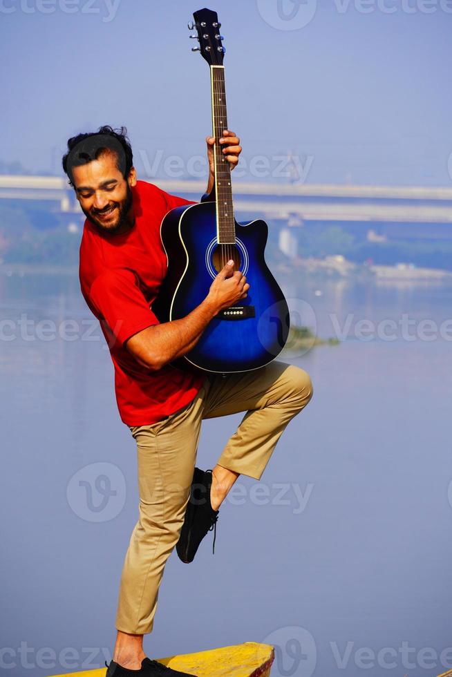 man spelar akustisk gitarr på båten. foto