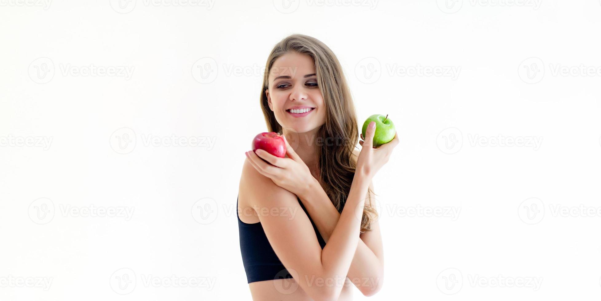 ung kvinna, smal figur som håller grön och röd äppelfrukt, klädd i svarta kläder, tränar foto