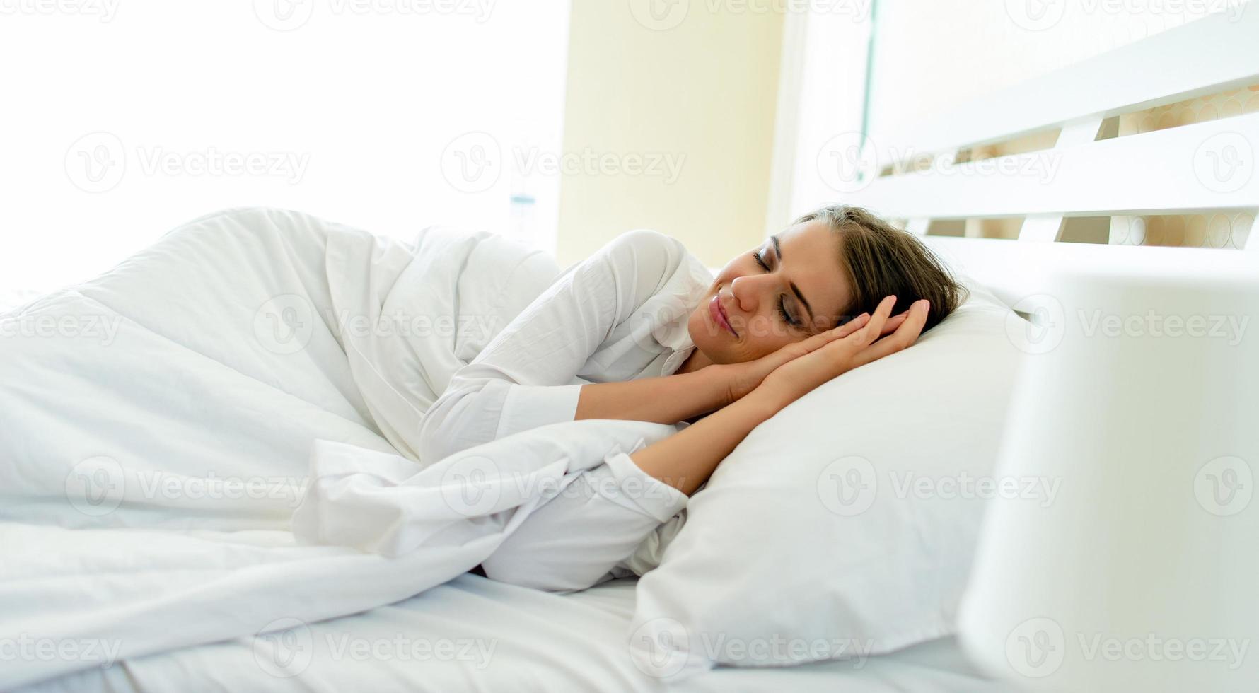 sovande kvinna från sidan av en vacker kvinna som ligger på sängen med slutna ögon medan täckt med ett filtfoto av vilande kropp foto