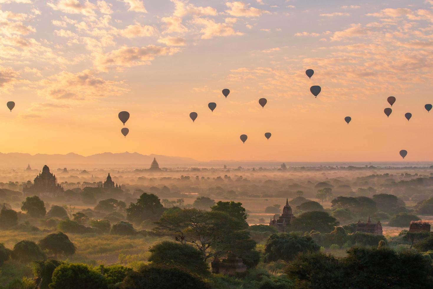 grupp av luftballonger som flyger över forntida pagod i bagan slätt i gryningen. Bagan är nu UNESCOs världsarv och Myanmars första kungarike. foto