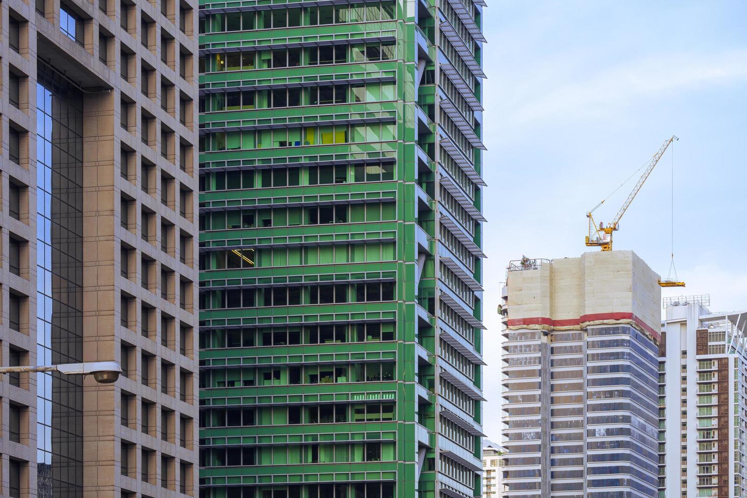 fokus på förgrunden vid raden av höga bostadshus med blå himmel i perspektiv från sidan att en byggnad är under uppbyggnad foto
