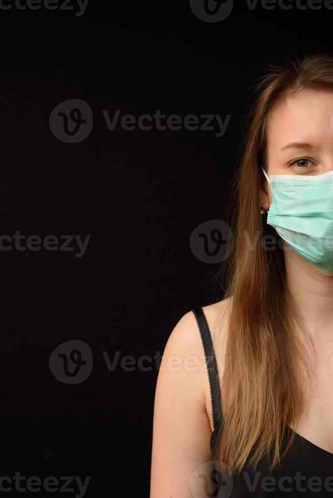 ung flicka i en medicinsk mask på en svart bakgrund. foto