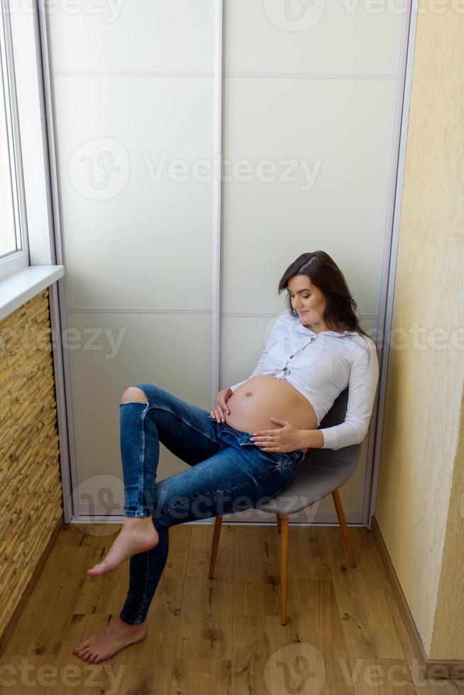 en man och en gravid kvinna sitter och kramas i soffan. foto