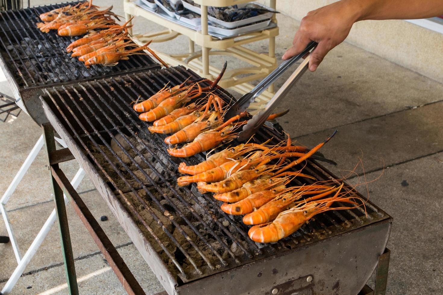 räkor på grillen med handen foto