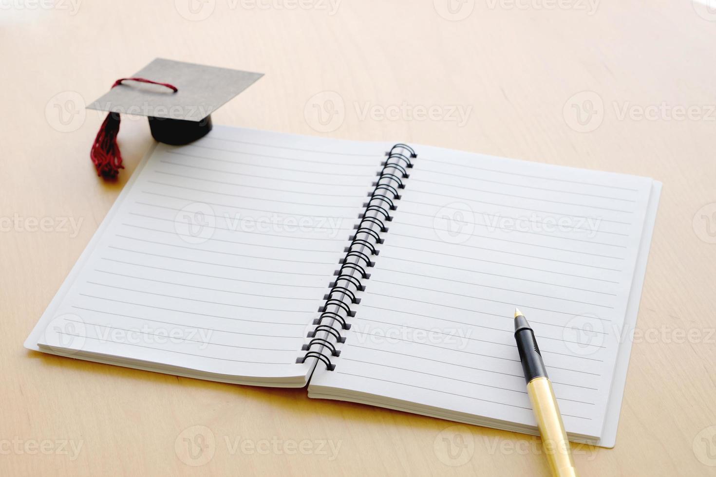 tom anteckningsbok på bordet och examenslocket foto