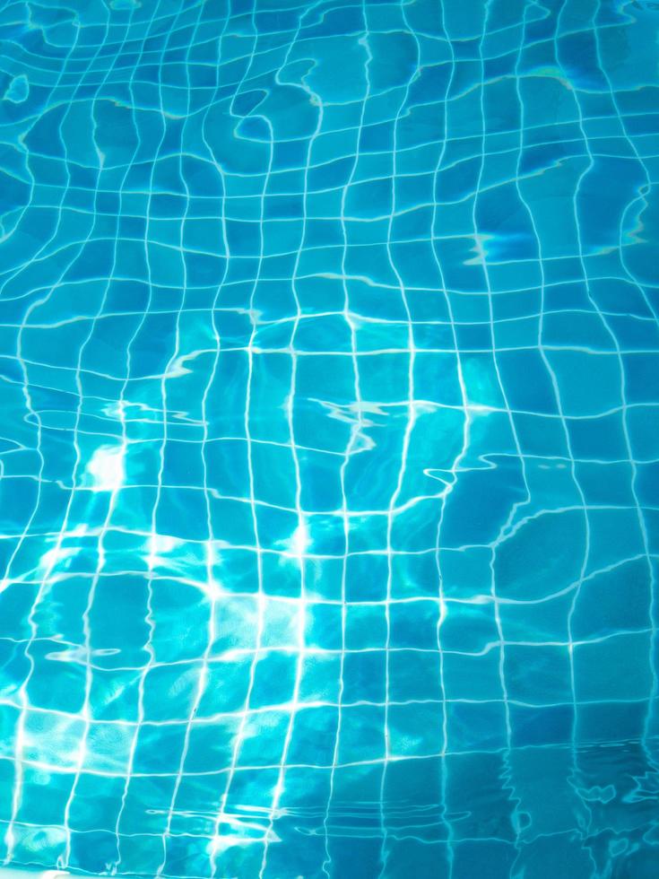 vattnet i poolen med ljus som reflekterar botten av poolen är en blå rutbräde. foto