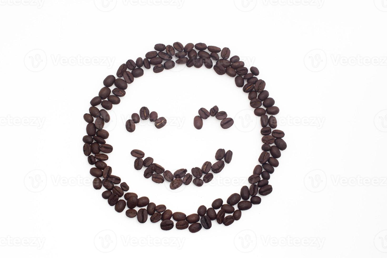 rostade kaffebönor arrangerade i ett leende ansikte på en vit bakgrund. foto