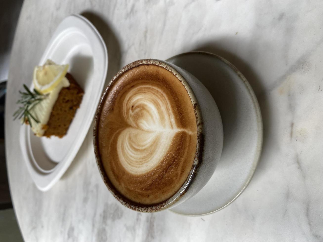 hjärta latte art på kaffekopp och tårta på träbord foto