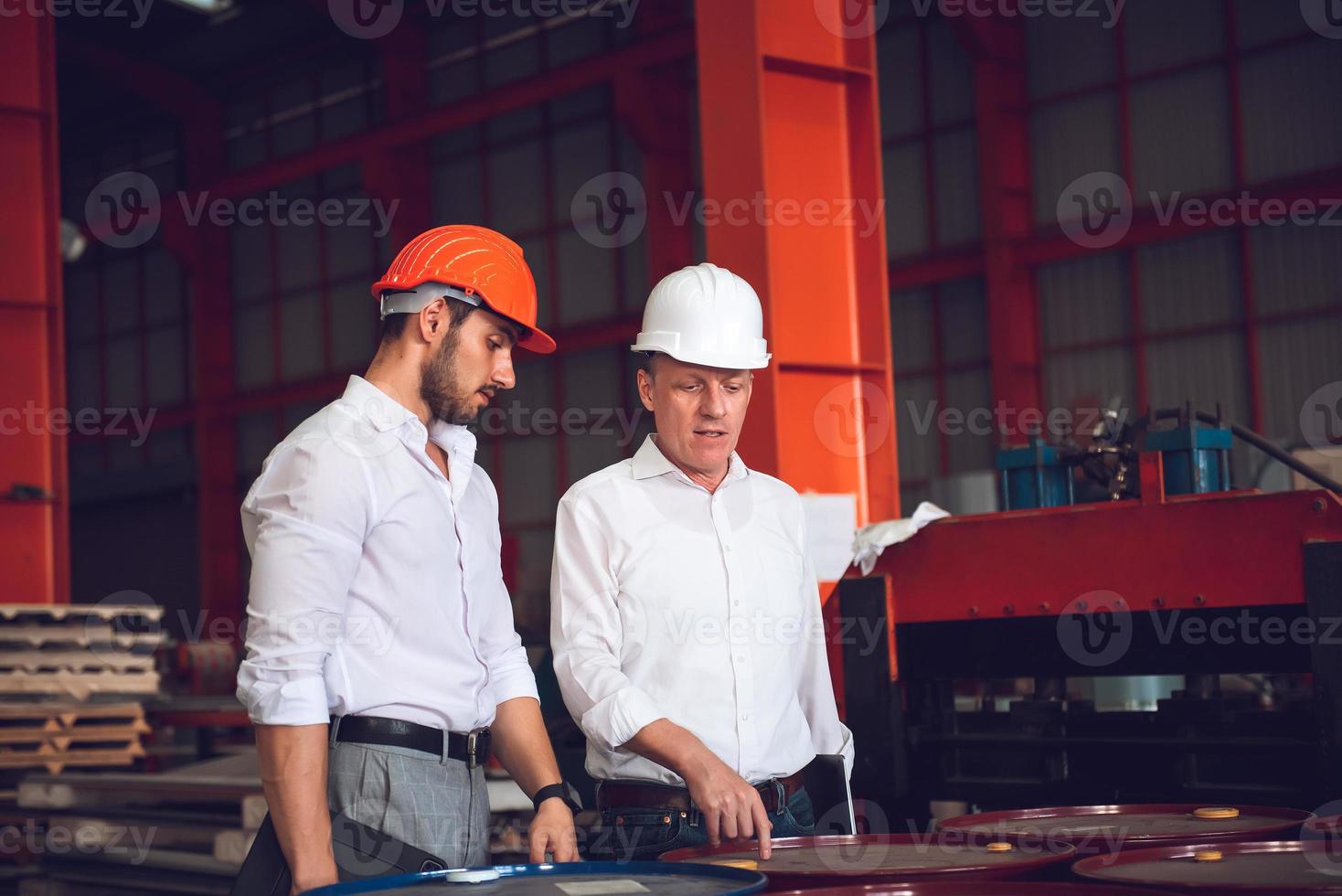 fabriksarbetare förman och ingenjörschef som arbetar tillsammans på industriarbetsplatsen, bär hjälm för säkerhets skull foto